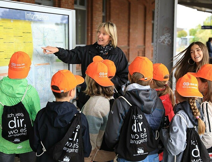 Schulkinder vor Fahrplantafel