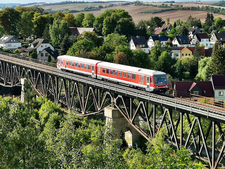 ein roteer Triebwagen der Baureihe 628 fährt über eine Eisenbahnbrücke