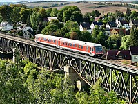 ein roteer Triebwagen der Baureihe 628 fährt über eine Eisenbahnbrücke