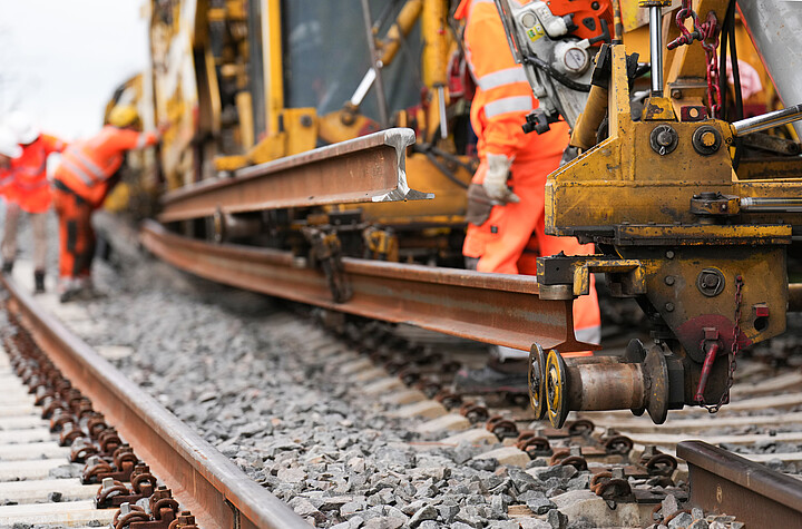Bauarbeiter und Baumaschinen auf einer Schienenbaustelle