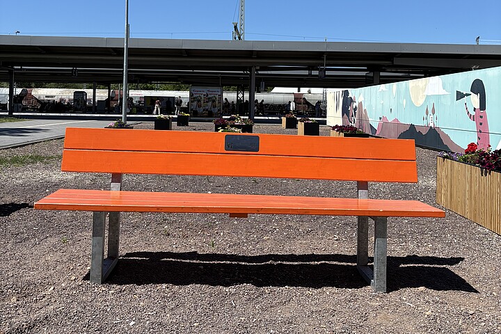 Eine Orange Bank steht auf einem Bahnsteig des Magdeburger Hauptbahnhofs