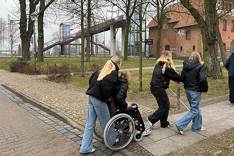 Eine Gruppe von Schülern. Einige Nutzen einen Roillstuhl oder Blindenstock