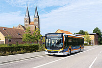ein Bus im orange-schwarz-weißen Mein-Takt-Design fährt am Kloster Jerichow vorbei